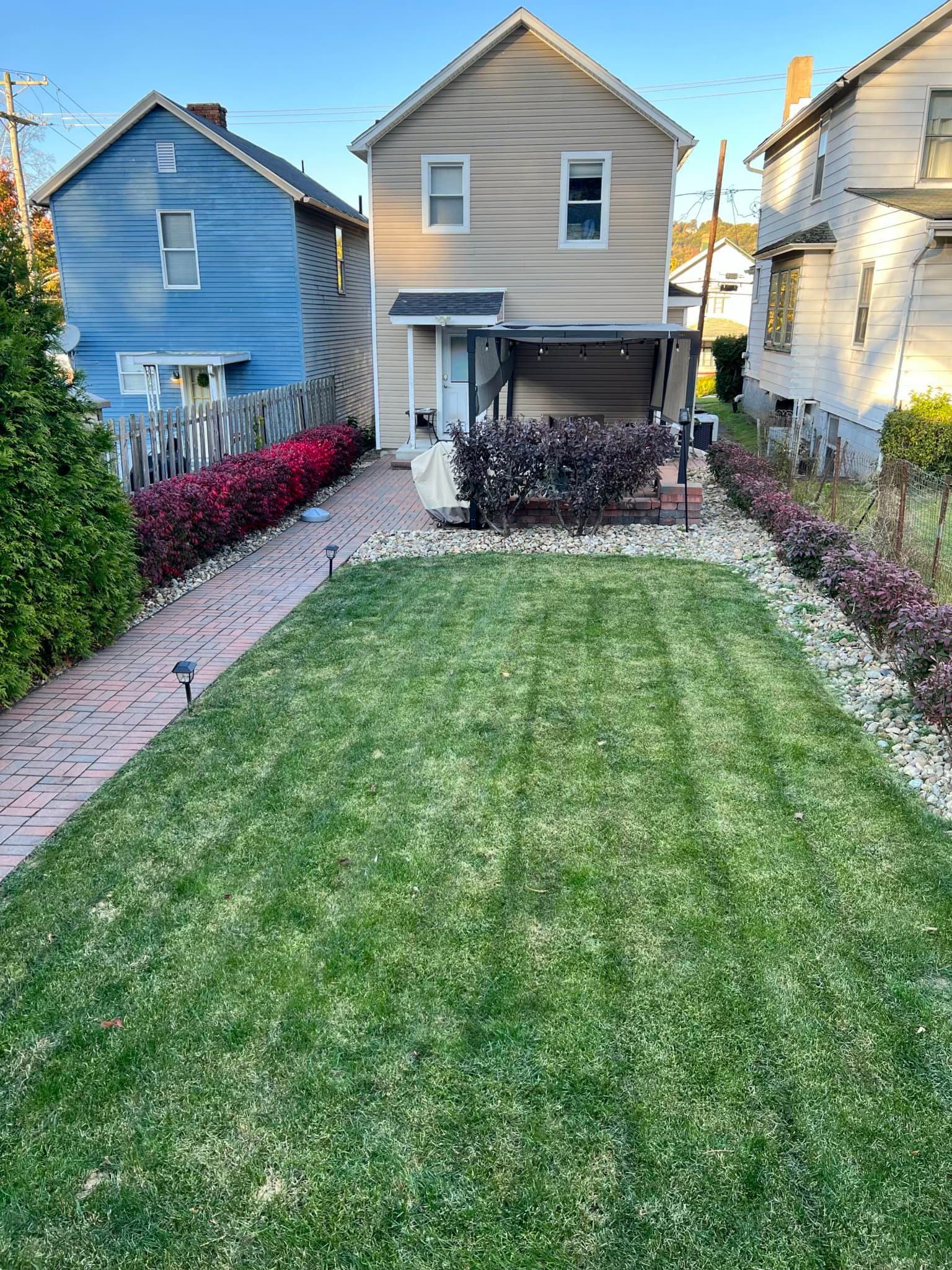 Landscaped backyard patio with pergola, paver path, and planting beds after renovation