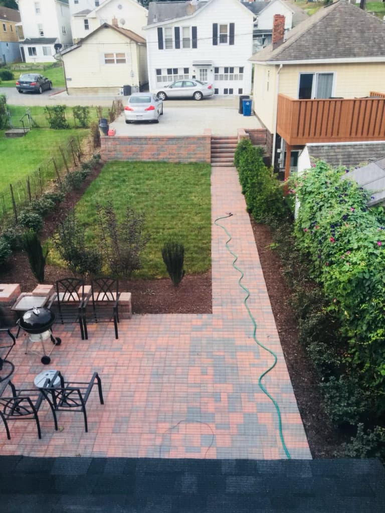 Overhead view of the new paver patio, walkway, and manicured lawn after renovation