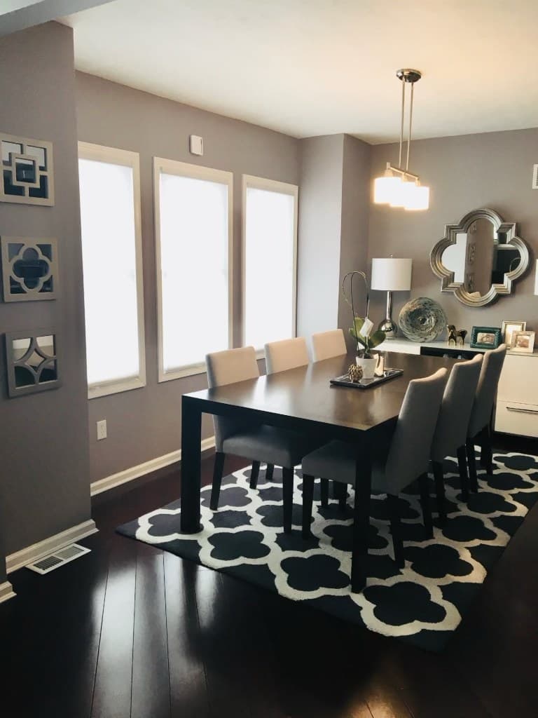 Dining room with a wall of windows, mirror gallery, and patterned rug after renovation