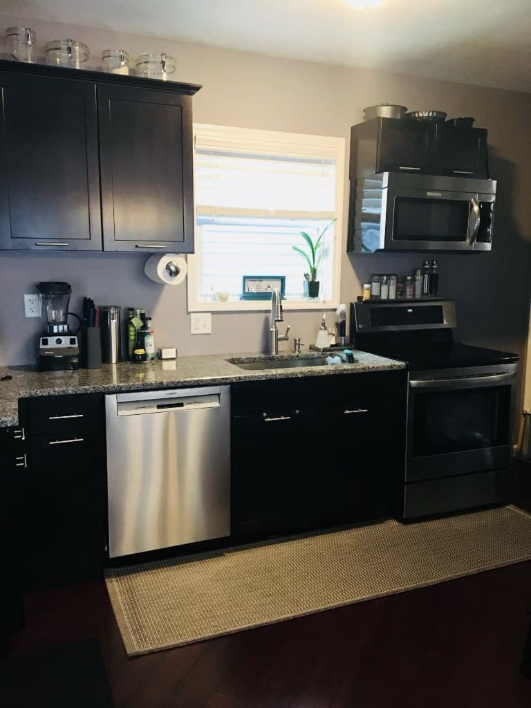 Rebuilt kitchen with dark shaker cabinets, granite counters, stainless appliances, and a window over the sink