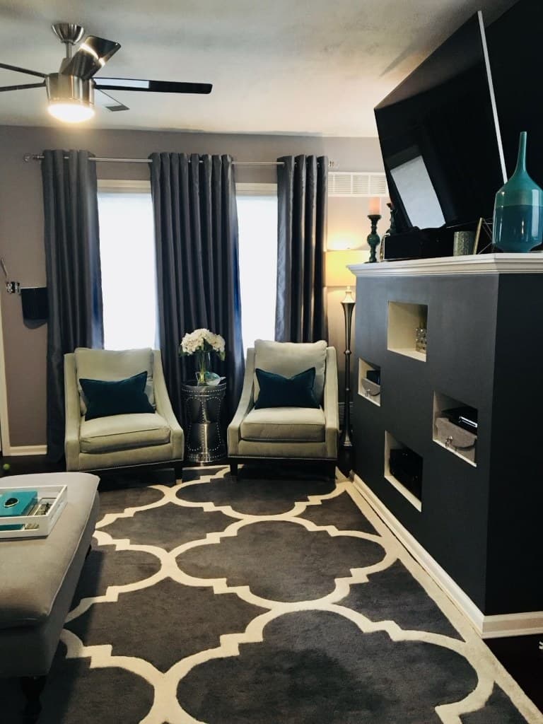 Modern living room with accent chairs, a patterned rug, and a built-in media wall after renovation