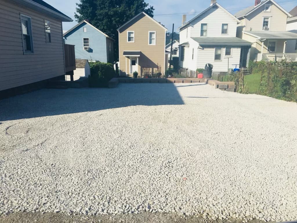 New white-gravel parking pad beside the house after renovation
