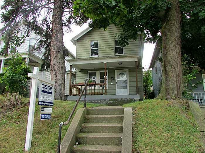 Green two-story Coraopolis house with a real-estate 'For Sale' sign, as purchased out of foreclosure