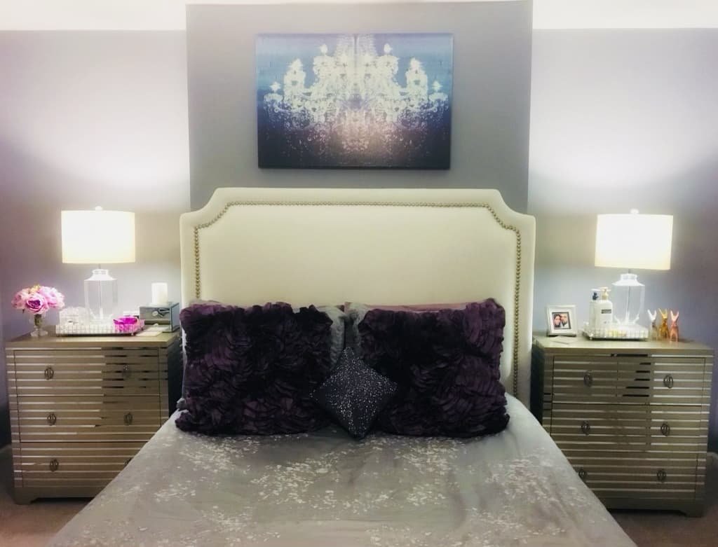 Serene bedroom with an upholstered headboard, mirrored nightstands, and layered bedding after renovation