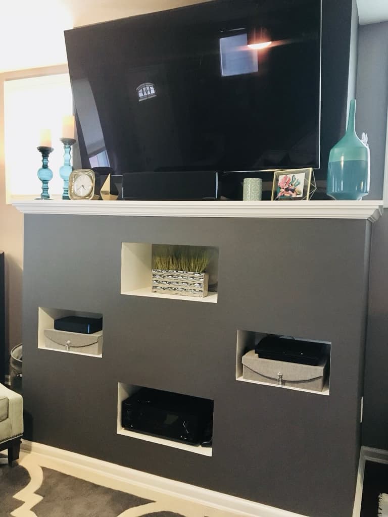 Custom gray media wall with a mounted TV, mantel shelf, and recessed AV niches after renovation