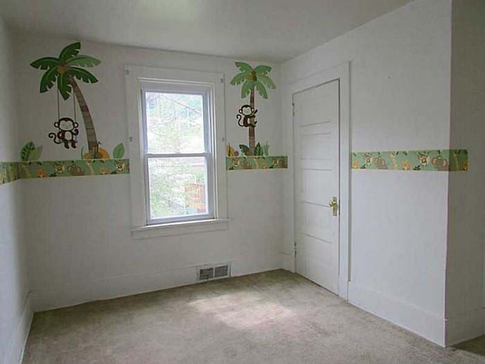 Bedroom with a jungle wallpaper border and palm-tree decals before renovation