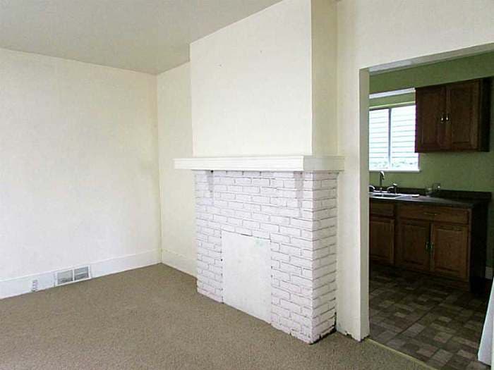 Painted brick fireplace beside the doorway into the dated green kitchen before renovation