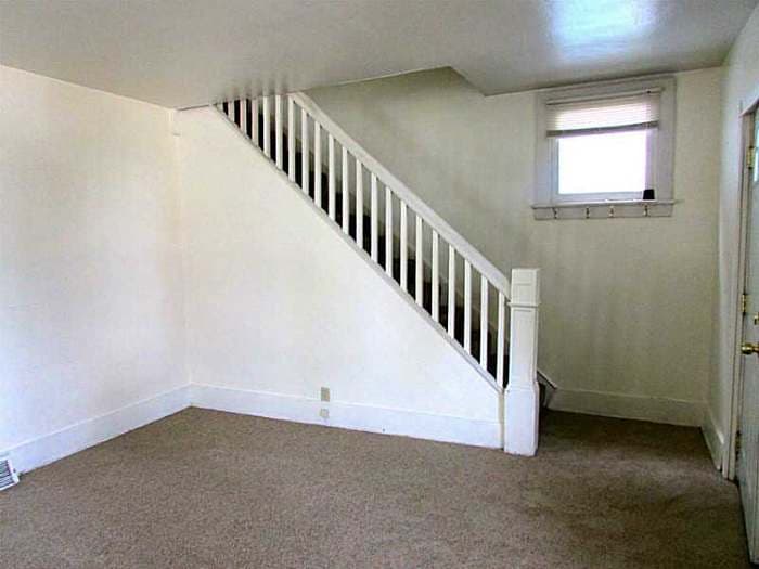 White-banister staircase and worn carpet before renovation
