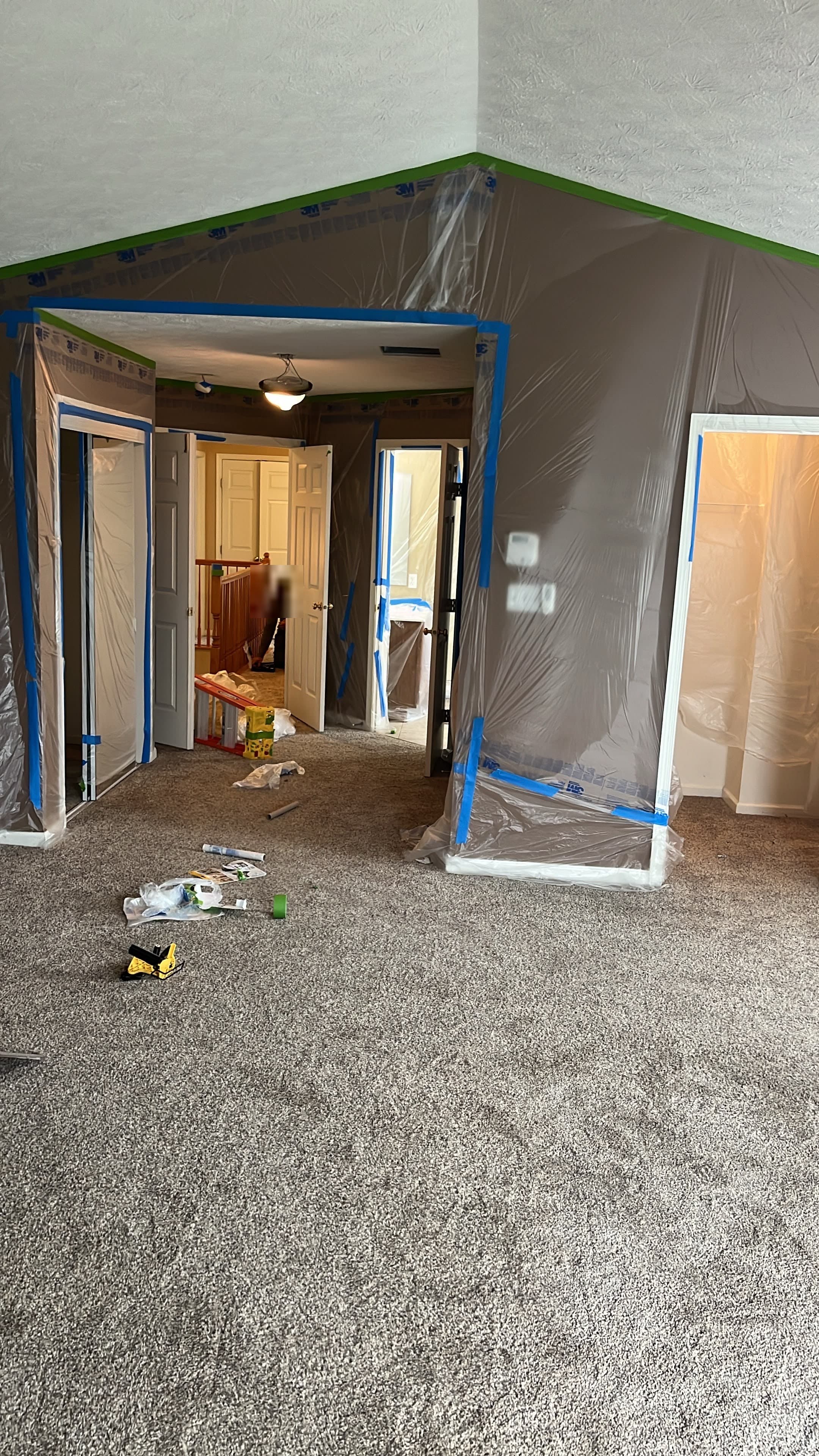 Vaulted loft ceiling with every wall and doorway masked in plastic during prep
